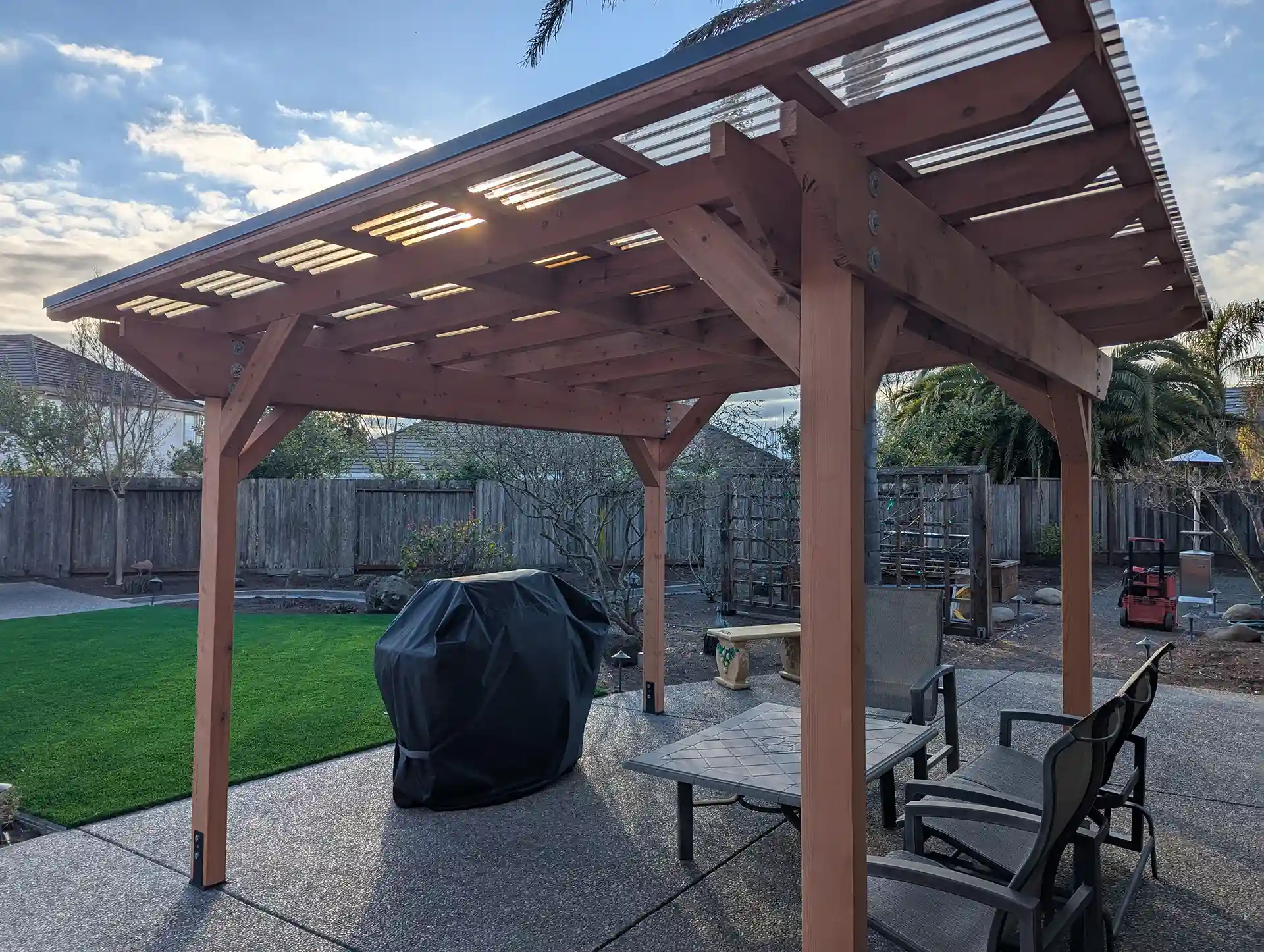 Redwood pergola with SunTough roofing over patio seating and grill area