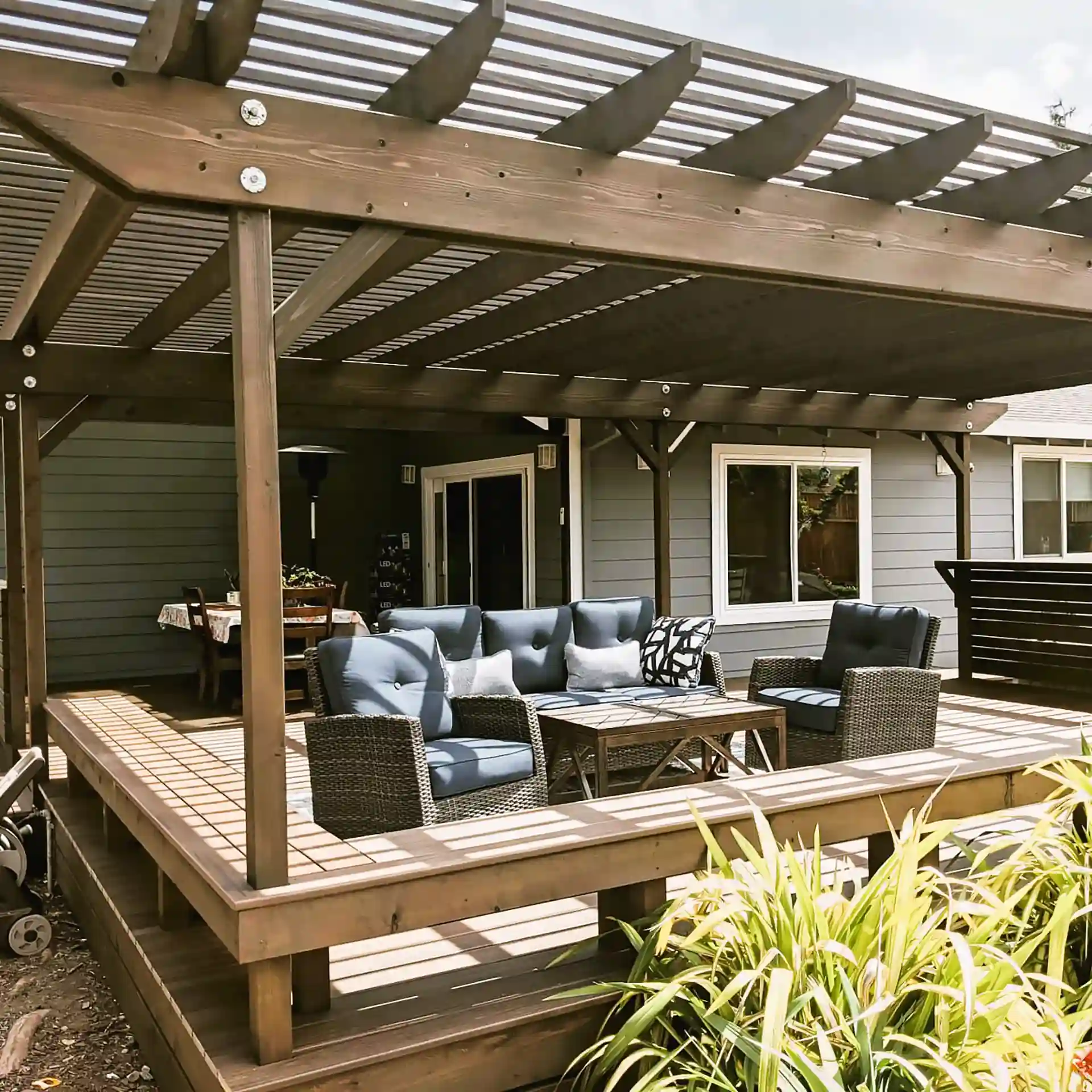 Wood deck with integrated seating and a large pergola structure, creating a shaded outdoor living area with lounge furniture