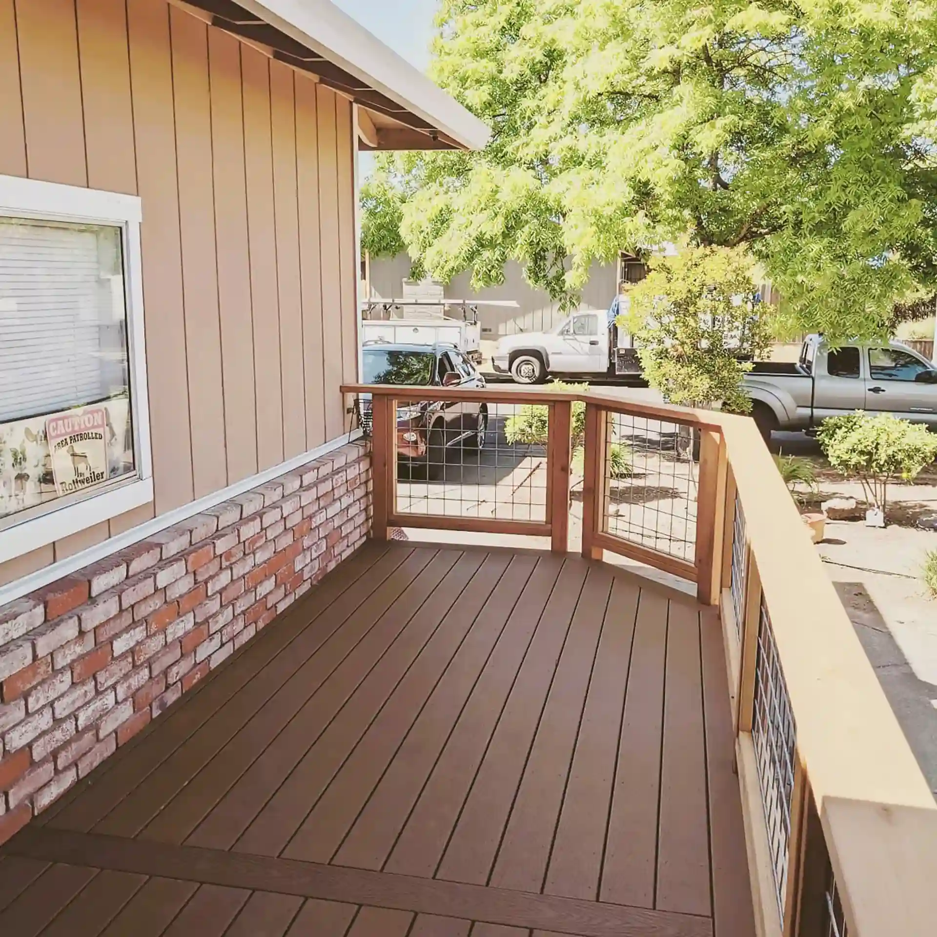 Trex composite deck with hog wire railing and redwood top rail, built alongside brick siding